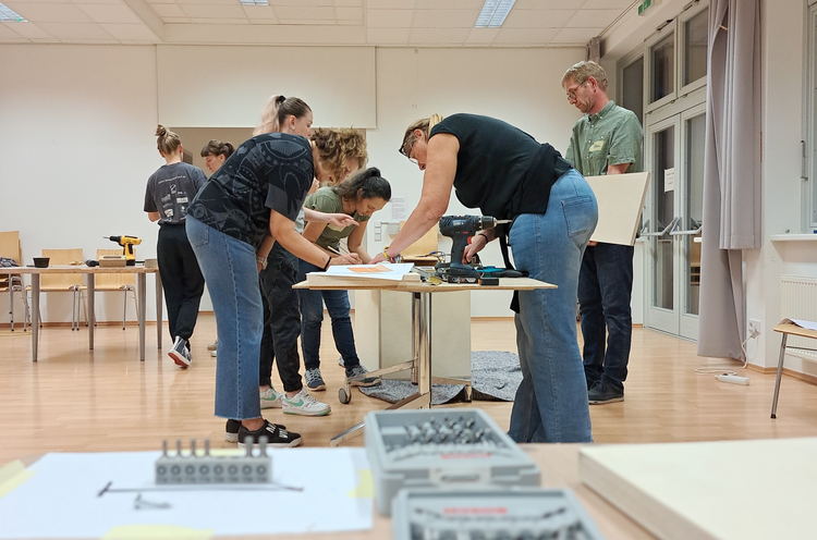 Mehrere Menschen arbeiten an einem Stück Holz.