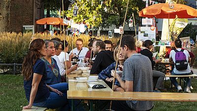 Menschen sitzen gemeinsam an einem Heurigentisch und unterhalten sich