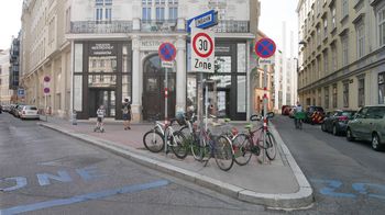 Theater aus der Gründerzeit, davor am Gehsteig Verkehrsschilder und parkende Fahrräder