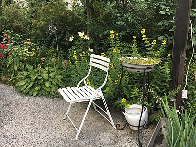 Begrünter Innenhof mit weißem Gartenstuhl