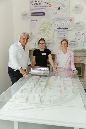 Drei Personen stehen hinter dem Modell des Stadtentwicklungsgebiets Oberen Hausfelds.