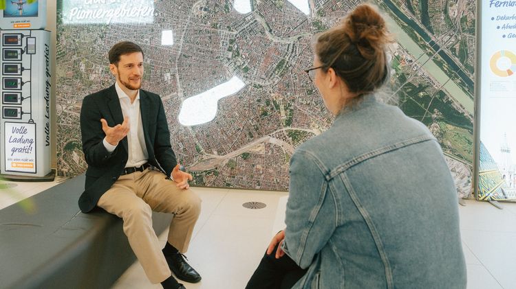 Wien Energie-Experte im Gespräch mit einer Mitarbeiterin der Gebietsbetreuung Stadterneuerung. Beide sitzen sich gegenüber.