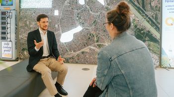 Wien Energie-Experte im Gespräch mit einer Mitarbeiterin der Gebietsbetreuung Stadterneuerung. Beide sitzen sich gegenüber.