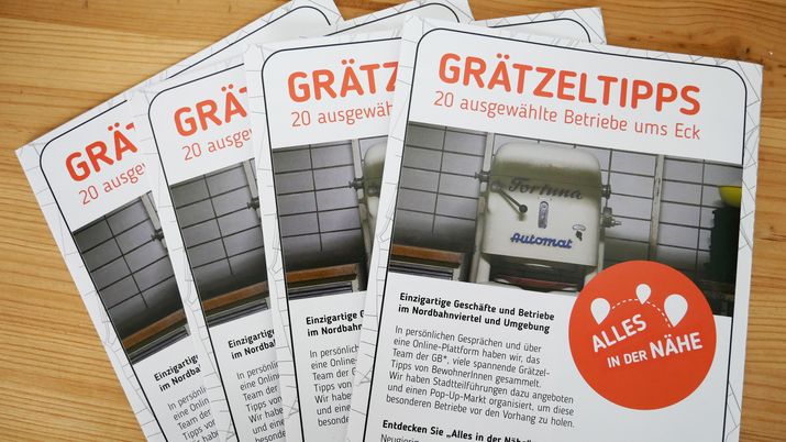 4 Folder mit der Überschrift "Grätzeltipps" liegen aufgefächert auf einem Holztisch