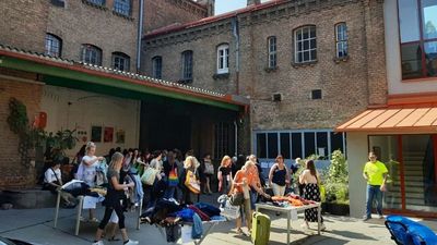 Viele Menschen vorm Backsteingebäude des Stadtteilbüros in der Quellenstraße 149. Sie tragen Stoffsackerl, reden und begutachten und tauschen Kleidung.