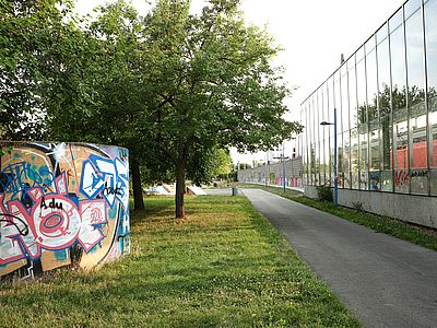 Gehweg zwischen der Ubahn-Linie U6 und einer Parkanlage.