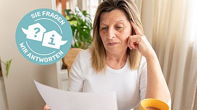 Frau liest eine Rechnung bei einer Tasse Kaffee.