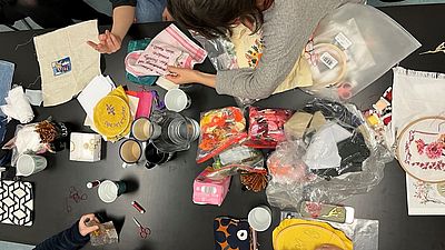 Eine Gruppe Frauen arbeitet an ihren Stickarbeiten gemeinsam an einem Tisch.