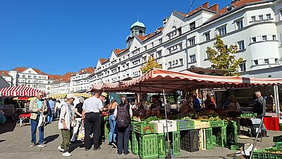 Marktstände mit Gemüse, Menschen kaufen ein