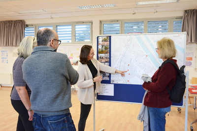 Die GB*Mitarbeiterin zeigt die beliebtesten Plätze in der Brigittenau auf einer Karte an drei Besucher*innen.