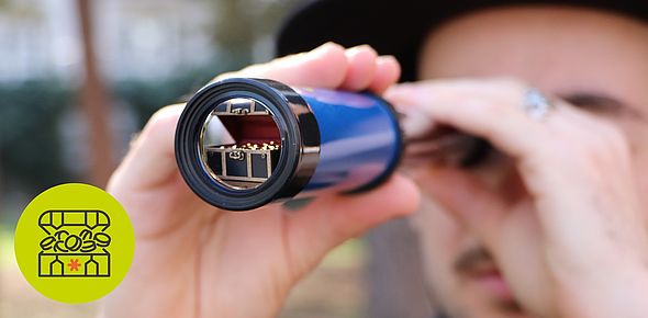 Eine Person blickt durch ein Fernrohr und sucht den „Nachbarschatz”.