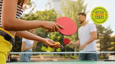 Menschen spielen Tischtennis im Freien. 