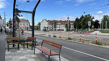 Sitzbank und Stühle an Straße mit Gerüst für Kletterpflanzen