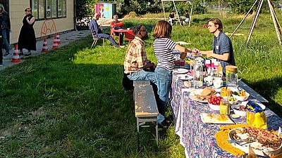 Auf dem Foto sieht man eine gedeckte Tafel mit Essen sowie Personen