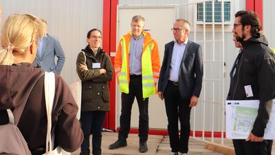 Führung auf die Baustelle, im Hintergrund Container