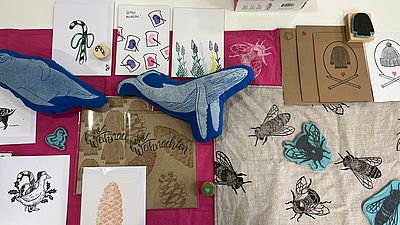 Stempeldruckzubehör und fertig bedruckte Textilien auf einem Tisch drapiert.