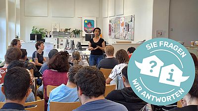 Junge Menschen sitzen mit dem Rücken zur Kamera und lauschen einem Vortrag der Wohnberatung zum Thema Mietvertrag und Wohnungssuche.