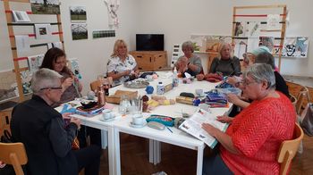 Frauen sitzen am Tisch und stricken