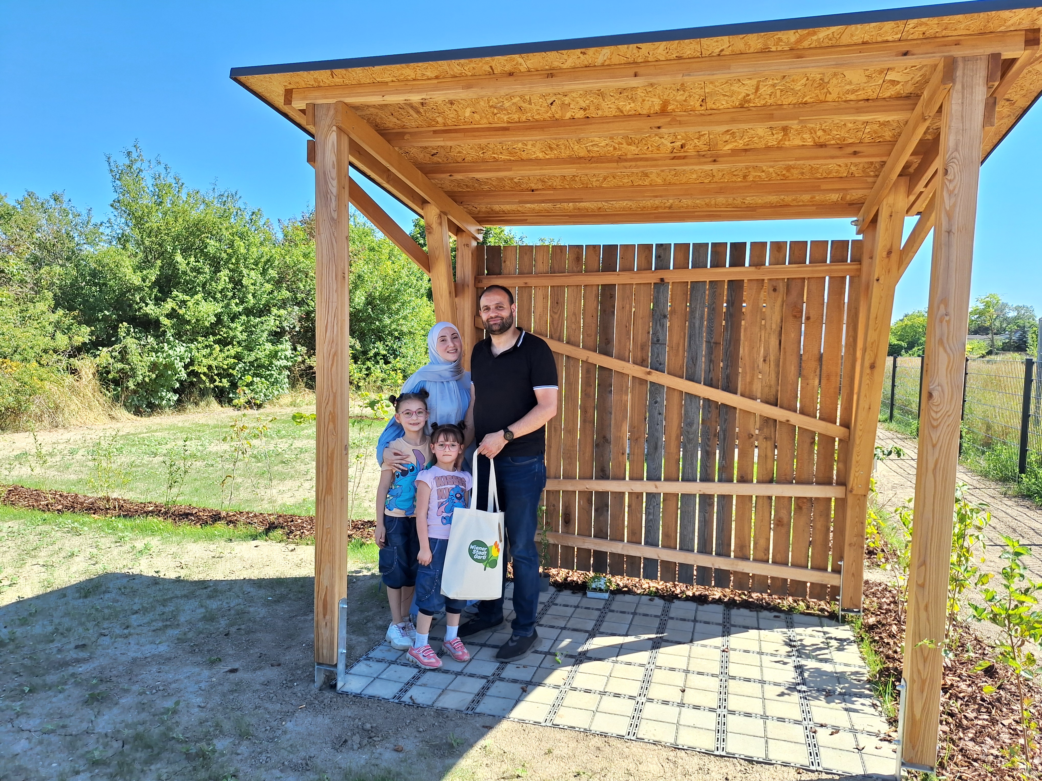 Eine 4-köpfige Familie posiert für das Foto in ihrer Gartenparzelle.